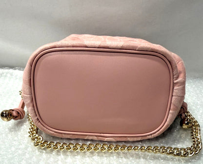Pink handbag with gold chain and 'Fancy Tokyo Tokyo' box on a textured surface